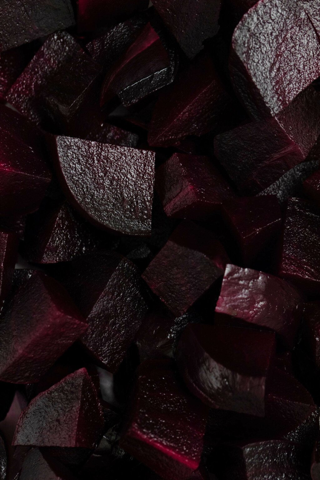 A zoomed in photograph of deep crimson red, cooked root vegetables.