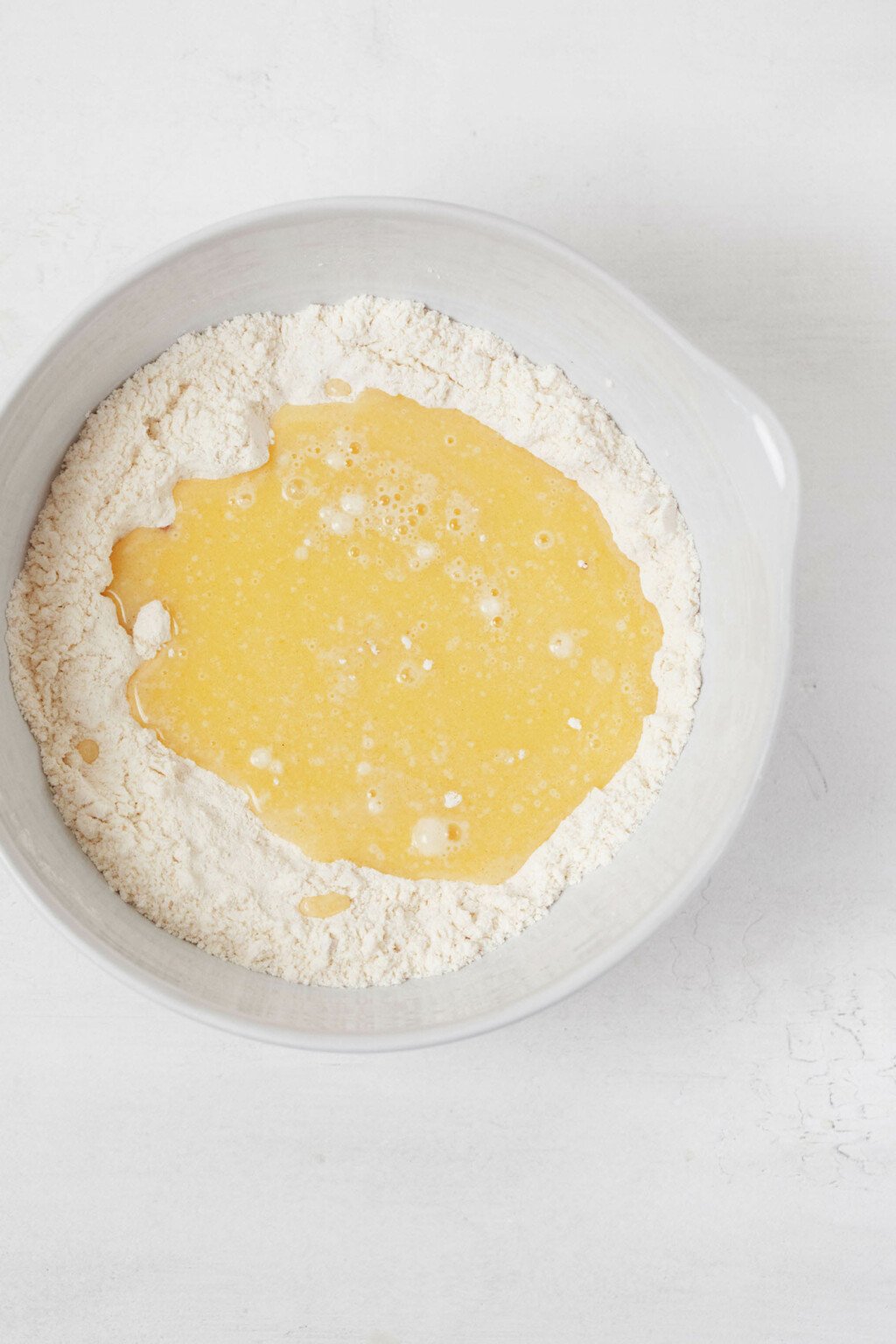 A muffin batter is being mixed in a large, white mixing bowl.