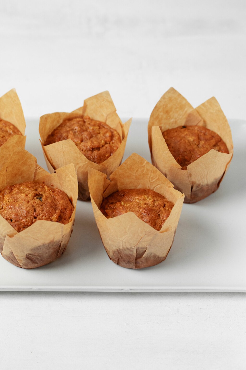 A white tray is lined with golden brown muffins in muffin liners.