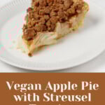 A hearty slice of vegan apple pie with streusel topping has been arranged on a small, round white plate.