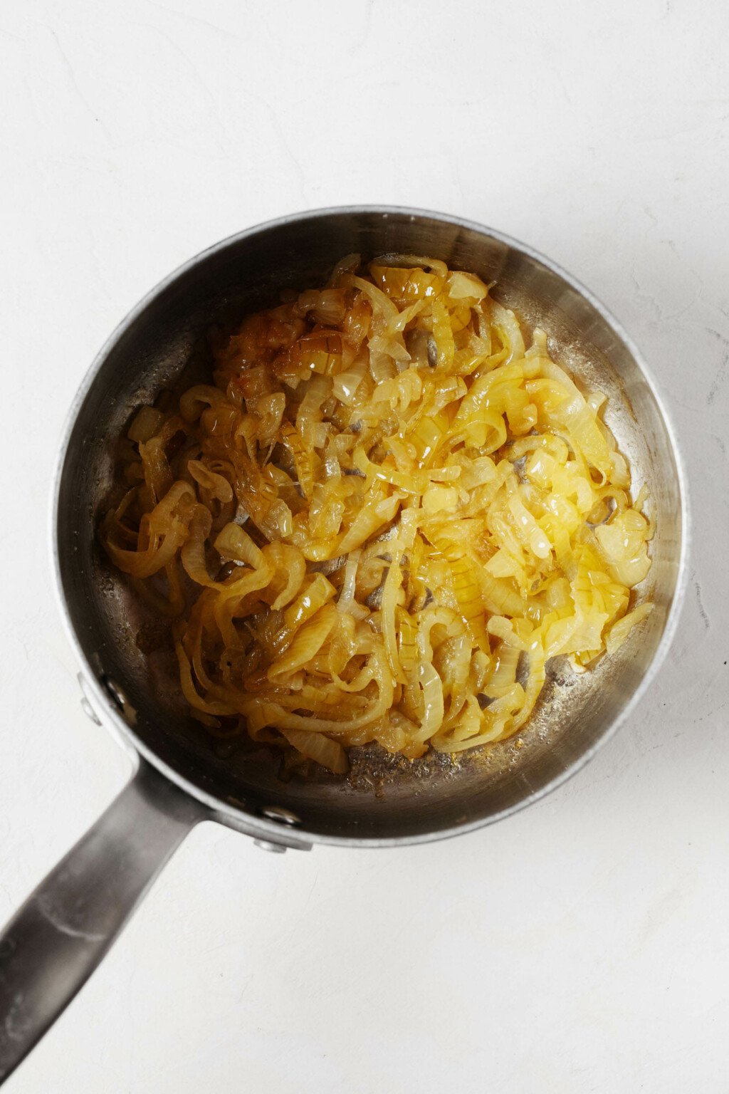 An overhead image of a silver soup pot, which is being used to caramelize onions.