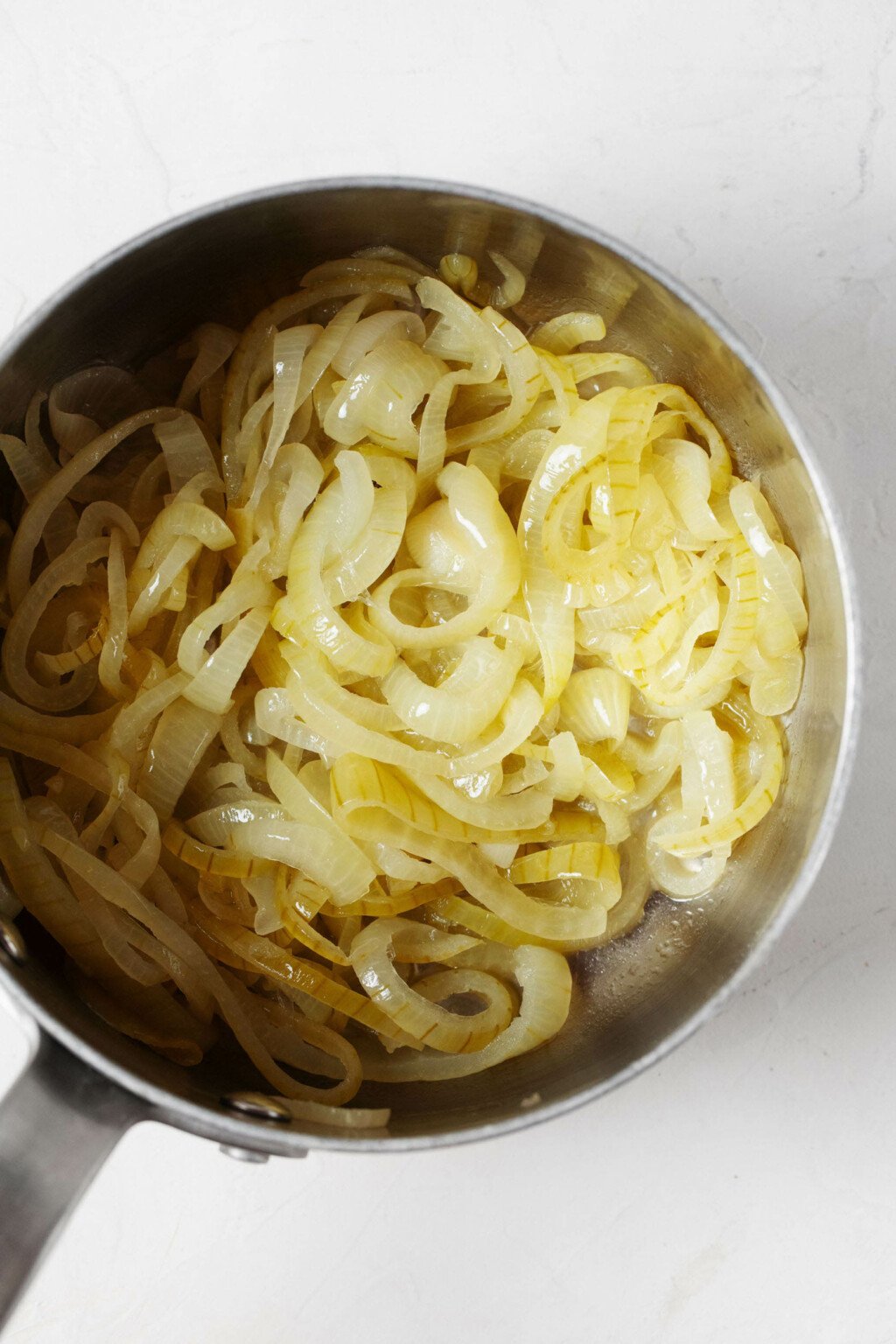An overhead image of a silver soup pot, which is being used to caramelize onions.