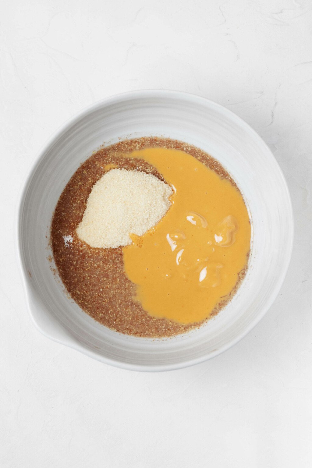 An overhead image of a white mixing bowl filled with flour, peanut butter, and other ingredients.