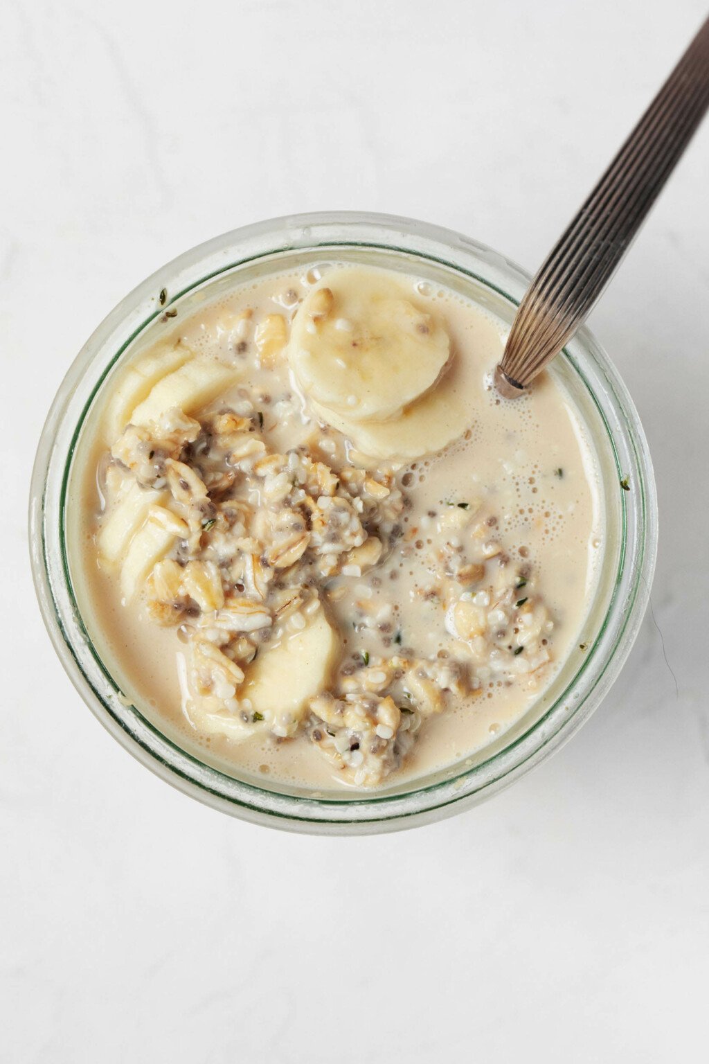 An overhead image of the mouth of a jar, which has been filled with plant-based overnight oats.