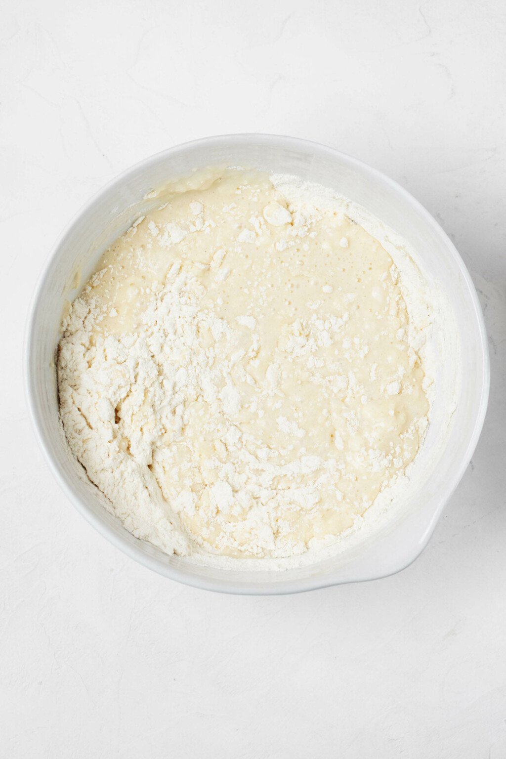 An overhead image of a large, white mixing bowl that's filled with a cake batter in the making.
