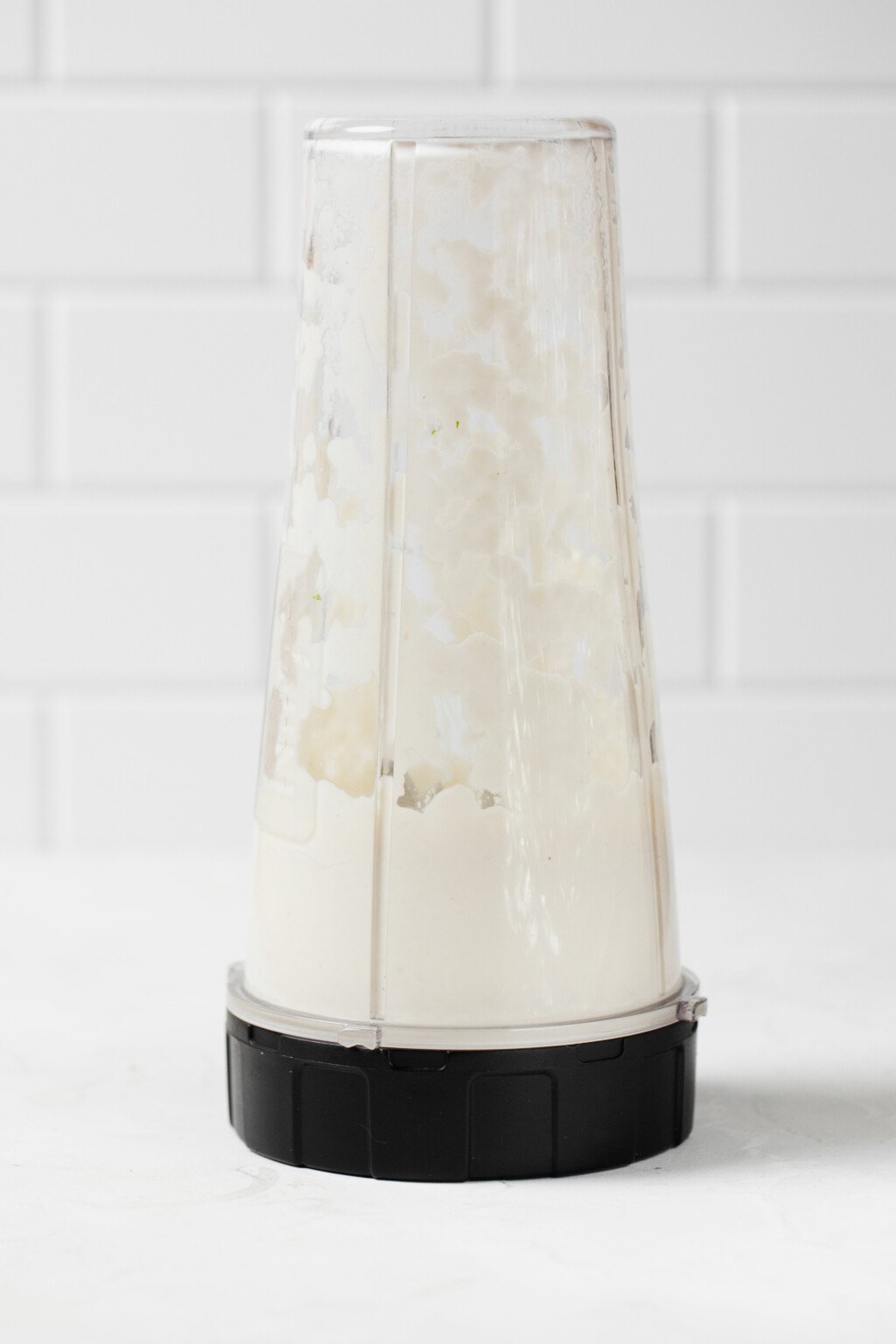 A personal sized blender is being used to blend a creamy dressing.