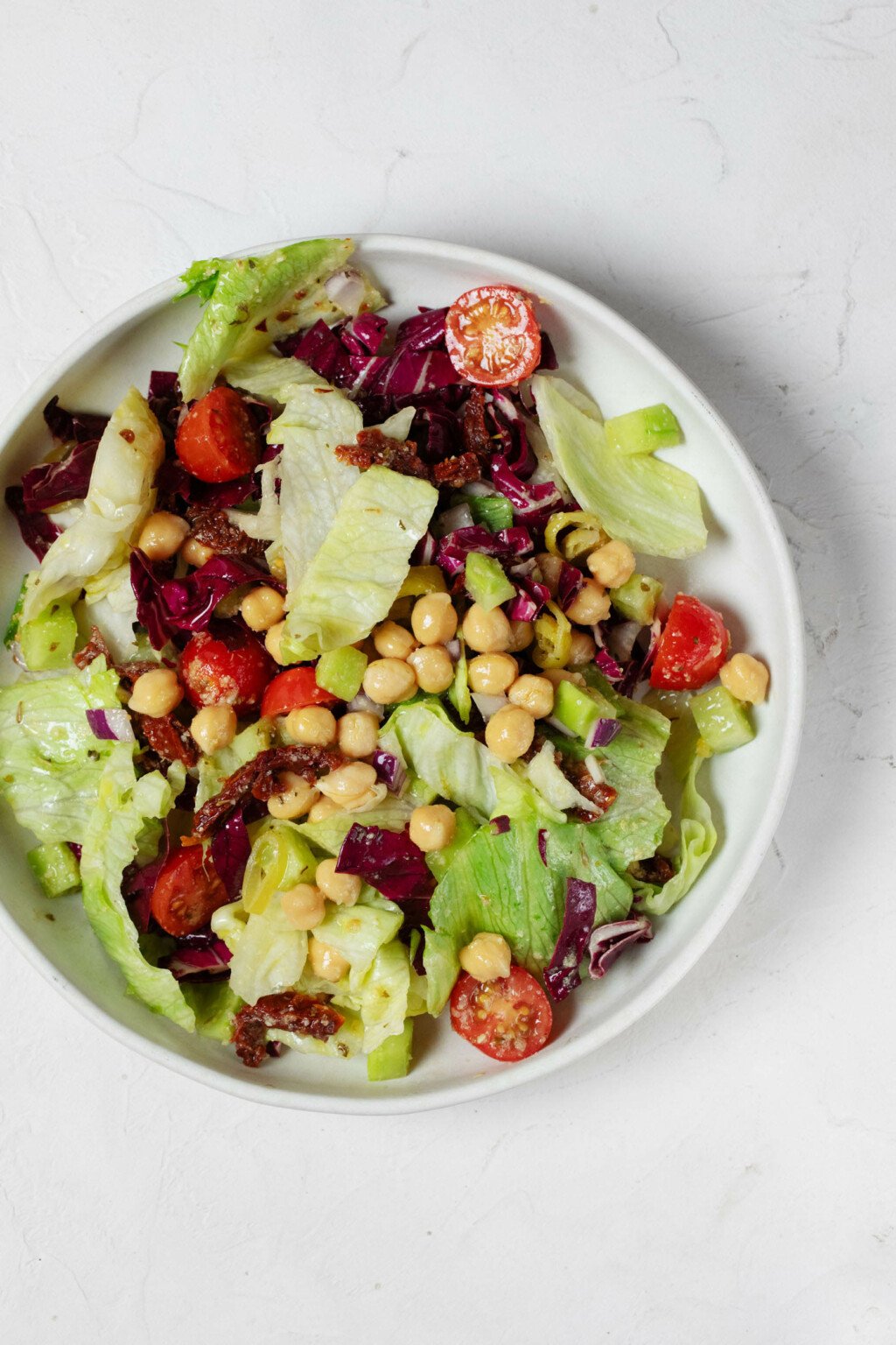 An overhead image of a white bowl, which has been filled with a colorful Italian chopped salad mixture.