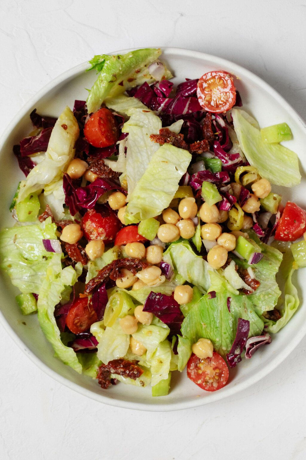 An overhead image of a white bowl, which has been filled with a colorful Italian chopped salad mixture.