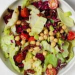 An overhead image of a white bowl, which has been filled with a colorful Italian chopped salad mixture.