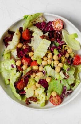An overhead image of a white bowl, which has been filled with a colorful Italian chopped salad mixture.