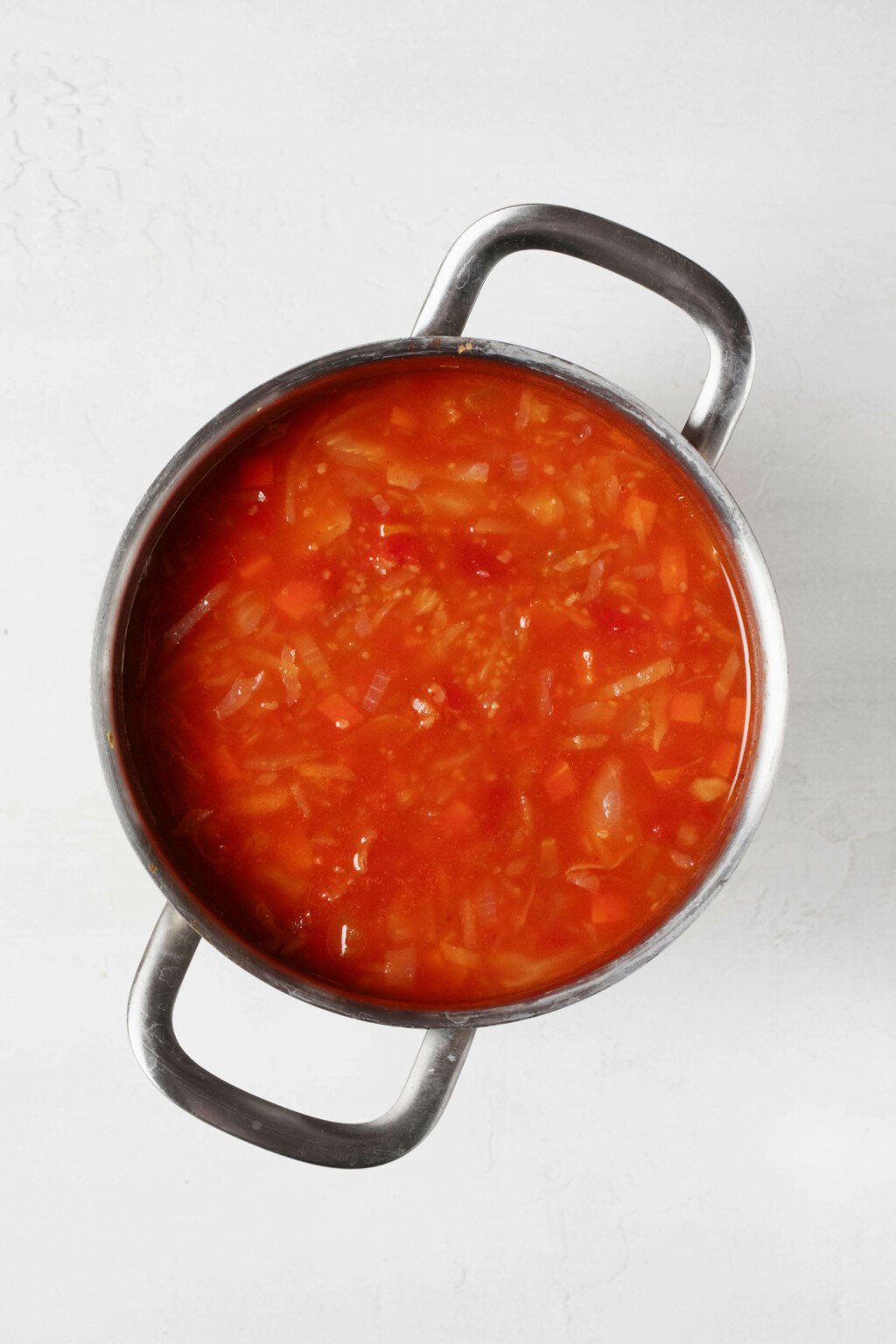 An overhead image of a silver pot, which is filled with a cabbage, bulgur, and tomato stew.