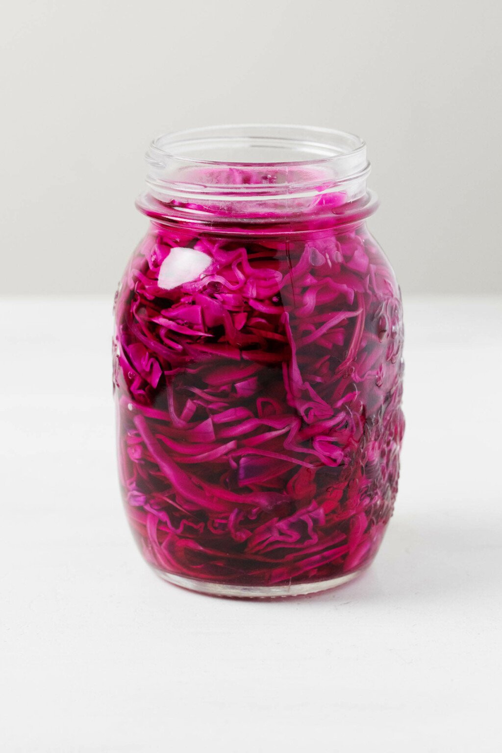 An angled image of a large mason jar, which has been filled with quick pickled red cabbage.