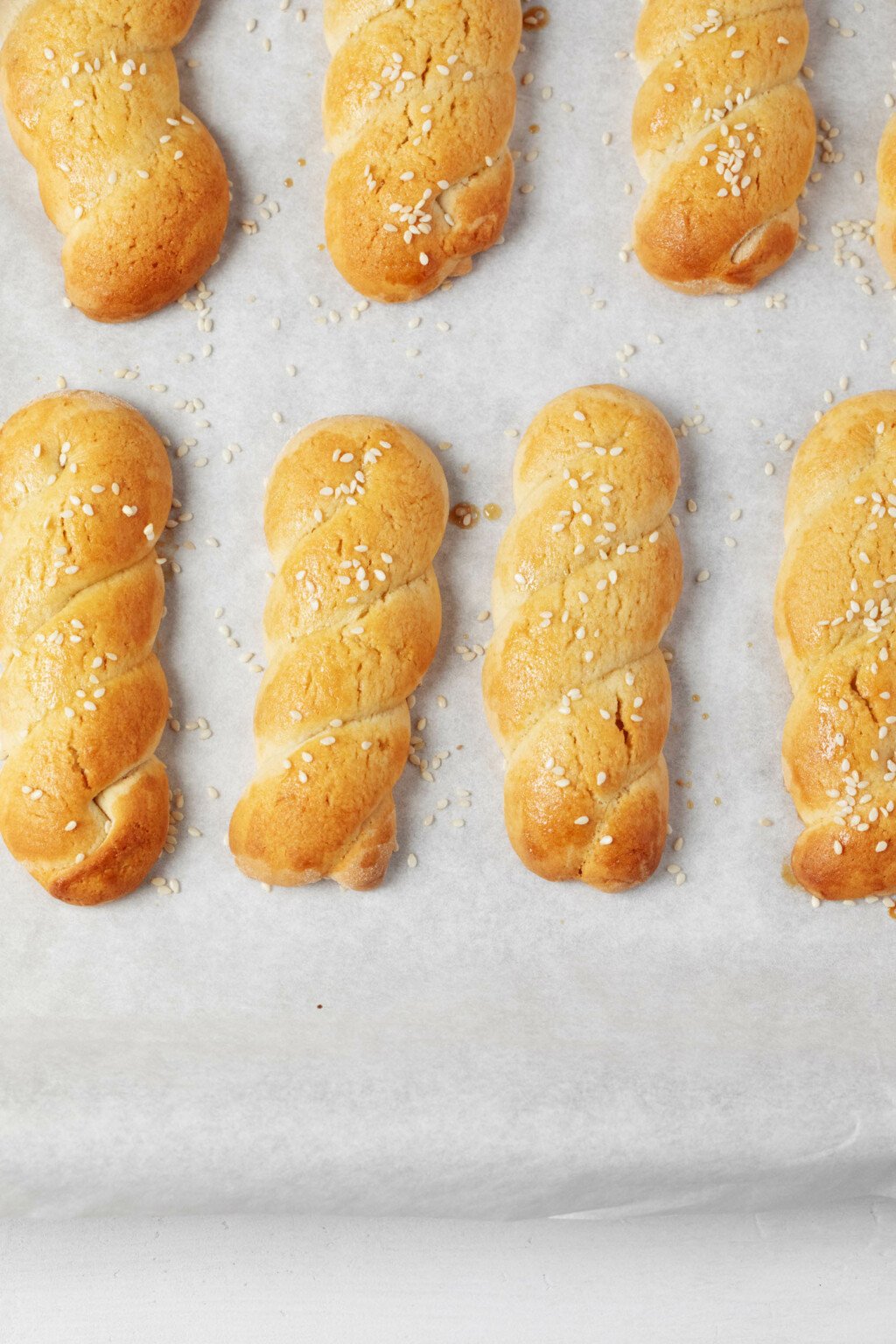 An overhead image of golden-brown, braided cookies on a parchment lined surface. 