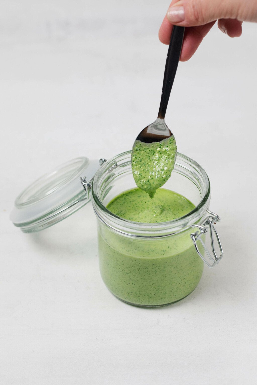 An image of a Weck mason jar, filled with a green tahini dressing.