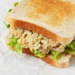 Two slices of white sandwich bread have been piled high with artichoke heart and chickpea-based vegan tuna salad.