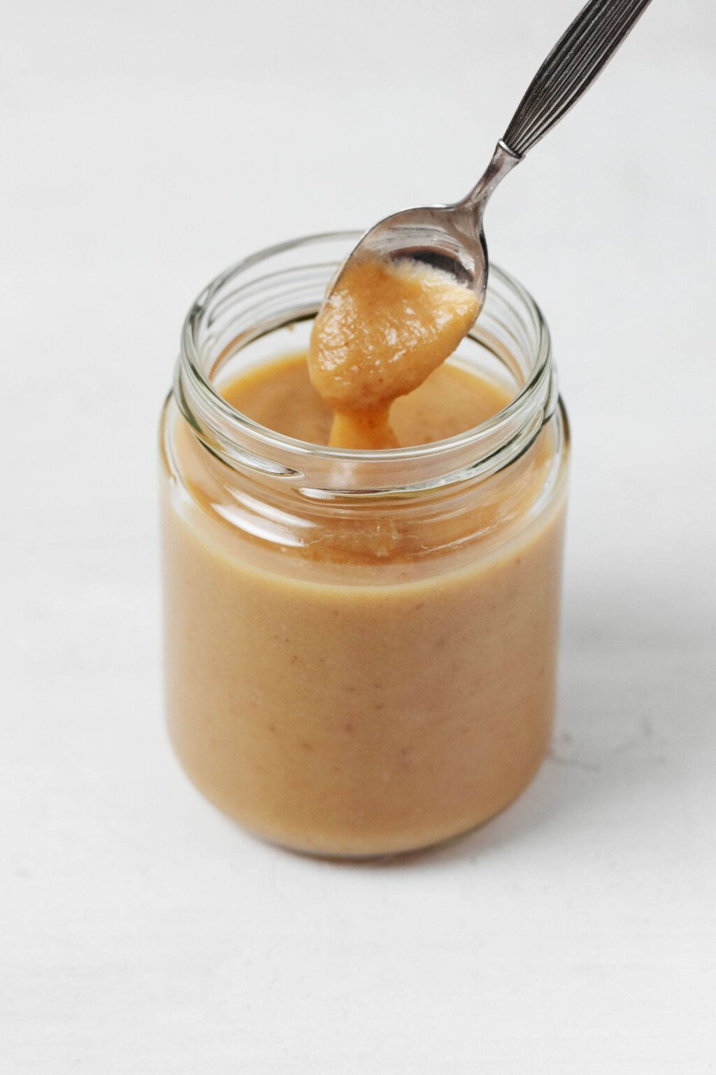 A creamy vegan caramel sauce is pictured in a glass jar.