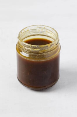 An image of a whisked balsamic vinaigrette, pictured in a clear mason jar.