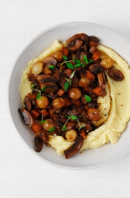 An overhead image of a dish of mashed potatoes, which have been topped with a vegan mushroom bourguignon.