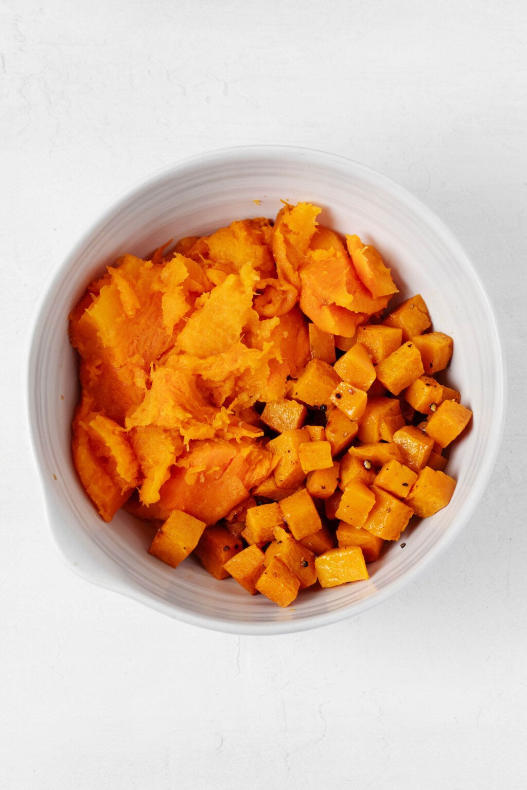 A large mixing bowl is filled with roasted winter squash and root vegetables. 