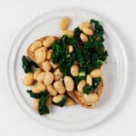 Plump butter beans and greens have been piled over toast.