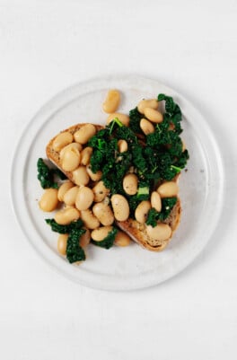 Plump butter beans and greens have been piled over toast.