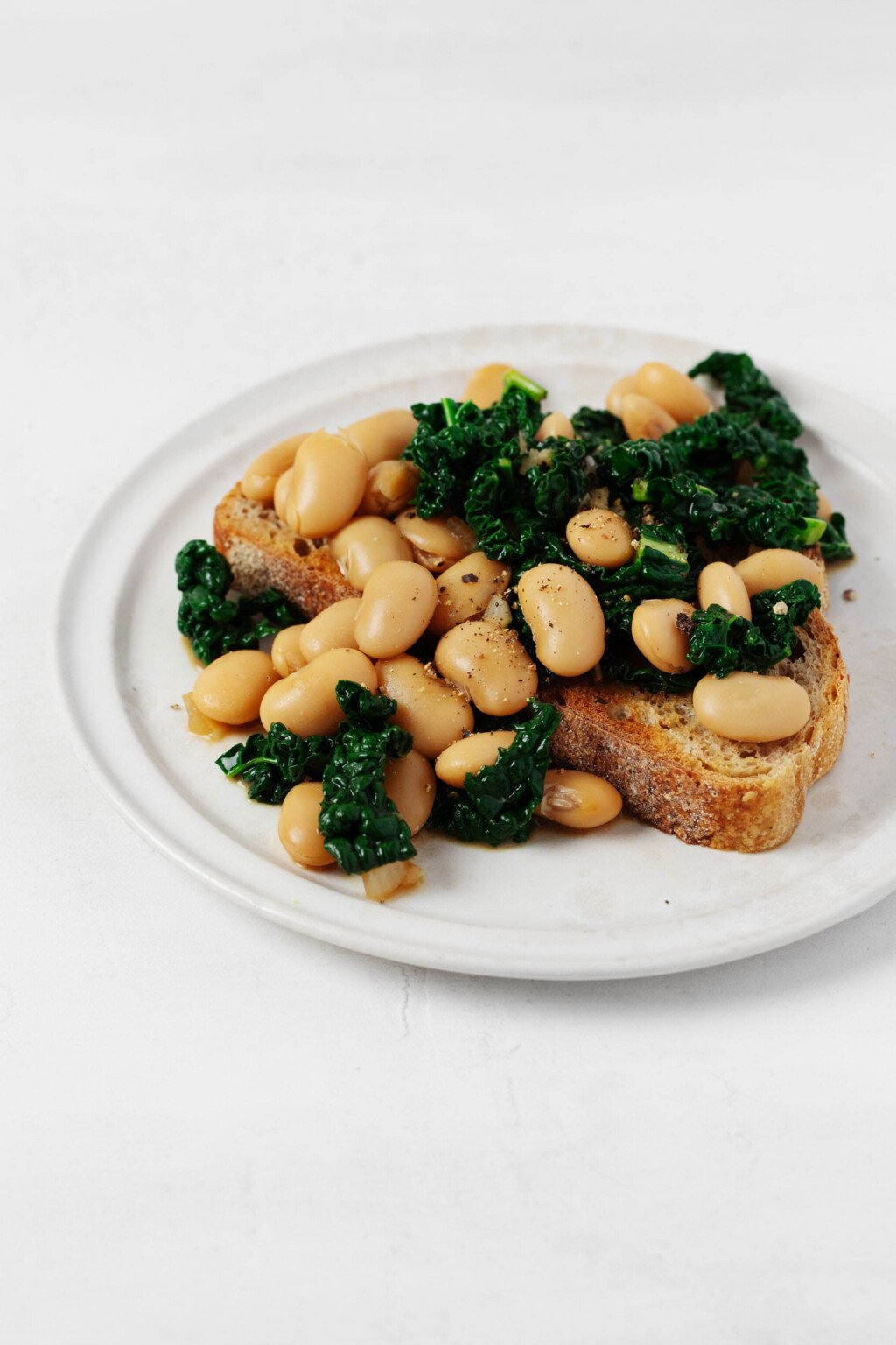 Plump butter beans and bright green kale have been piled over toast.