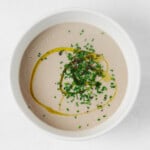 An overhead image of a round, white ceramic bowl that's holding pureed vegan cream of mushroom soup.